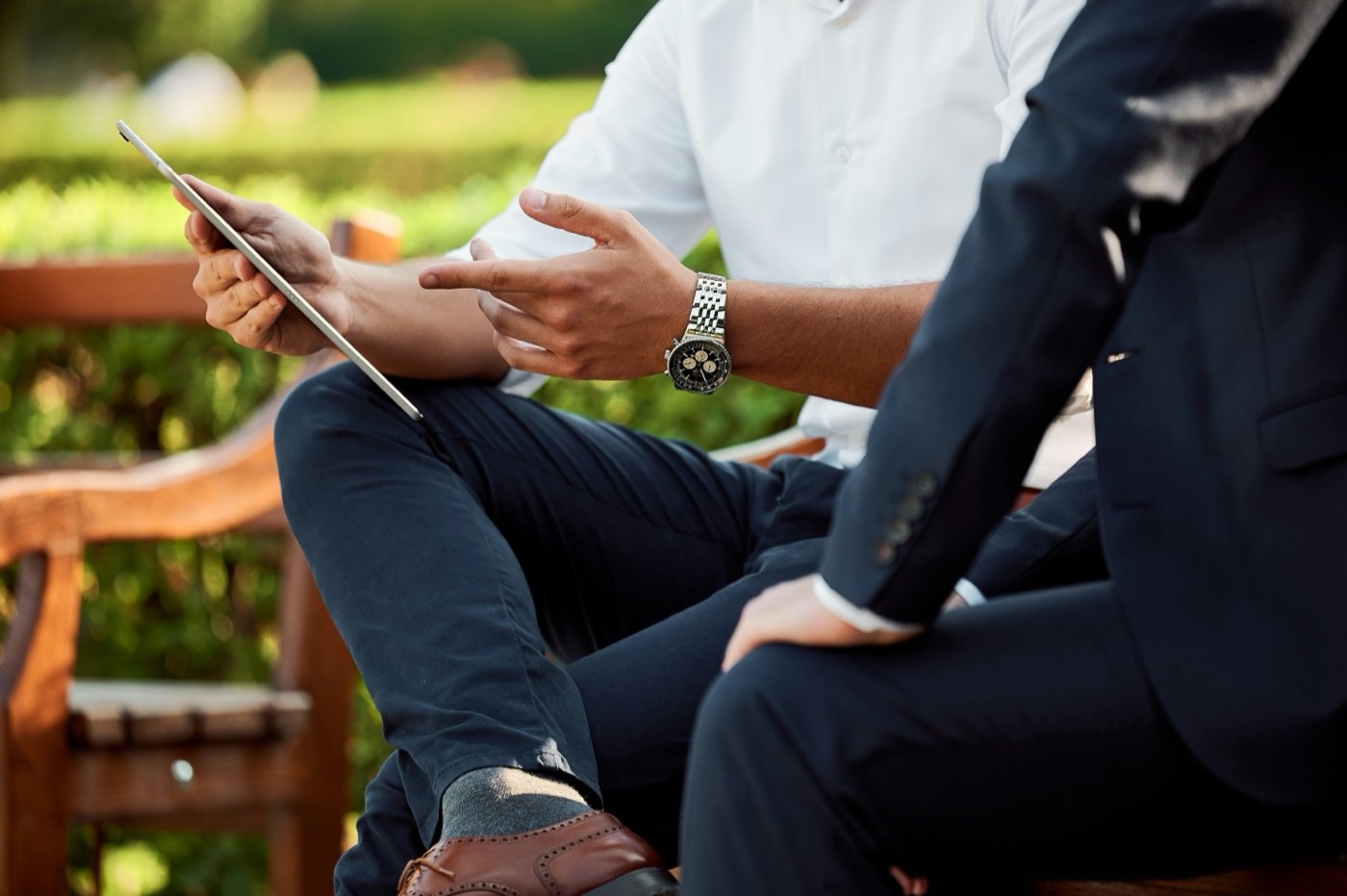 Two people seated outdoors on a bench, reviewing a policy together on a tablet