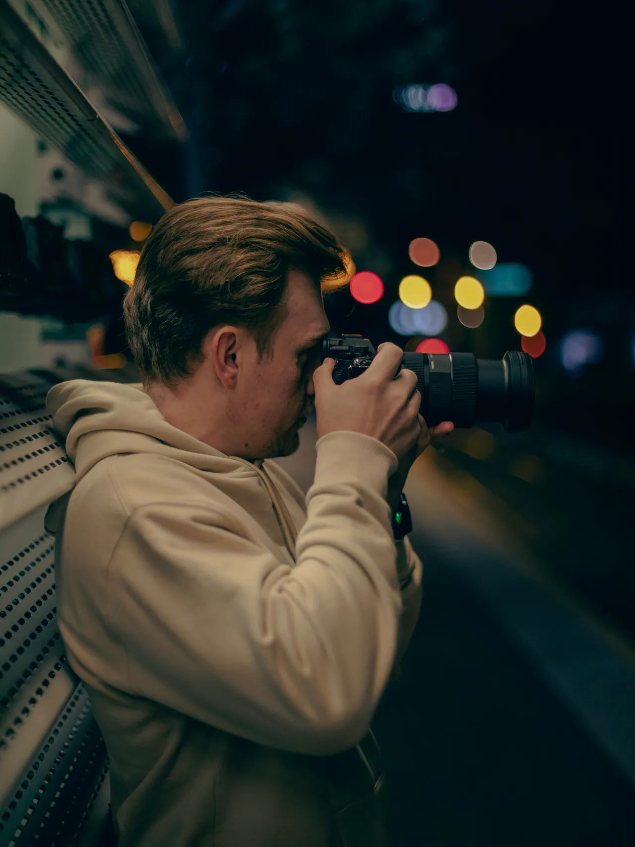 Photographer shooting at night with city bokeh behind him