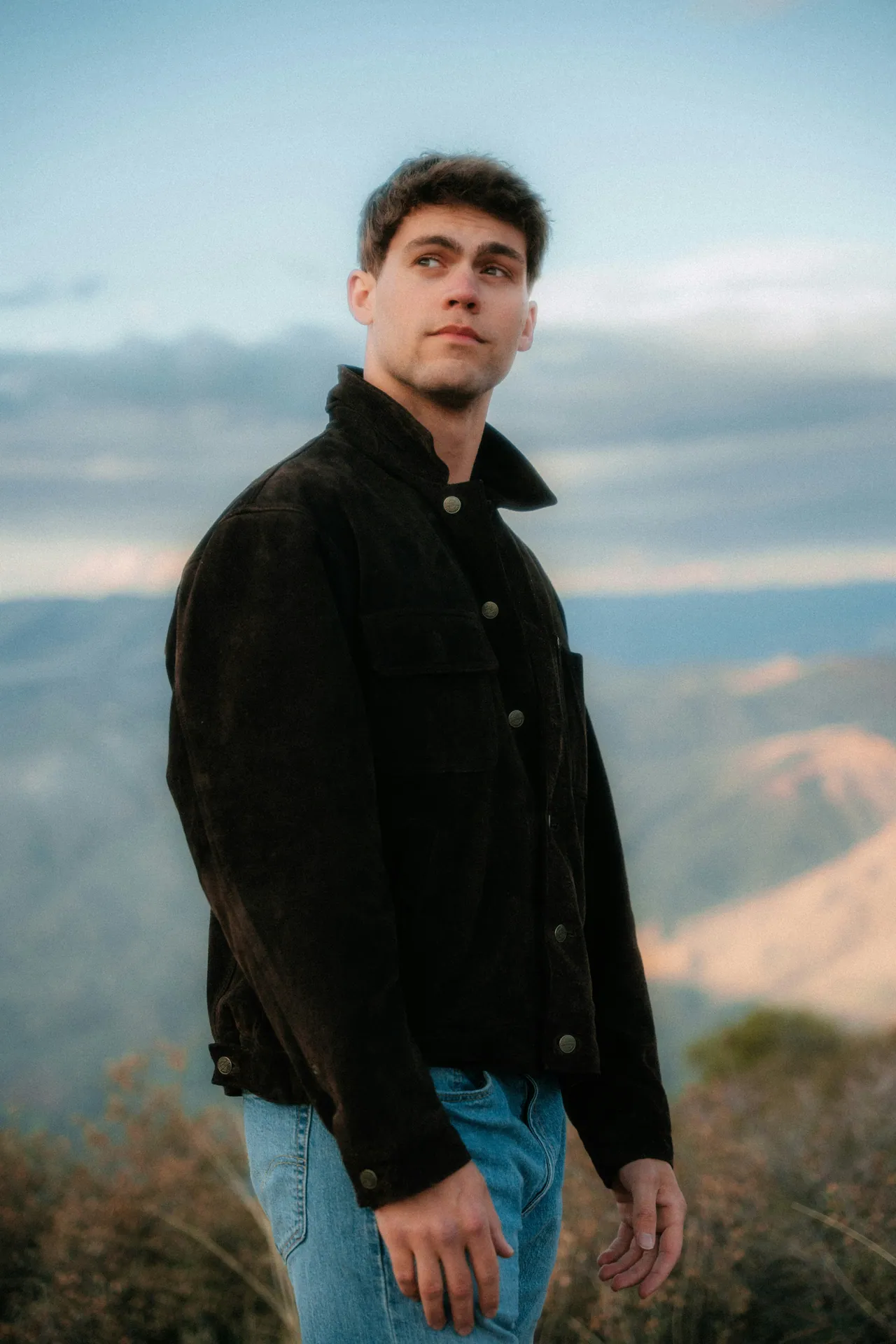 Man in a dark jacket on a ridge above a mountain valley